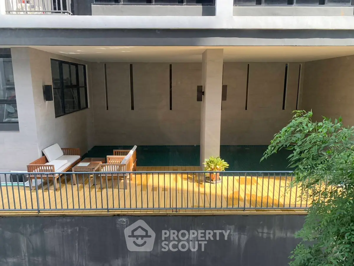 Modern apartment building with stylish poolside seating area and lush greenery.