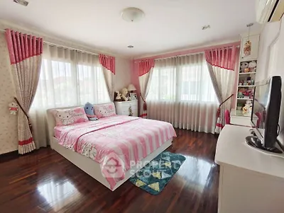 Charming bedroom with pink decor, large windows, and polished wooden floors.
