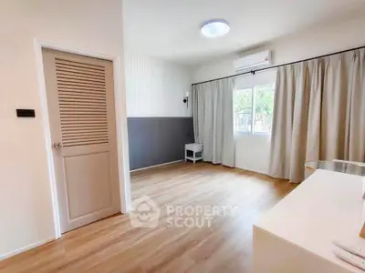 Spacious bedroom with wooden flooring and natural light