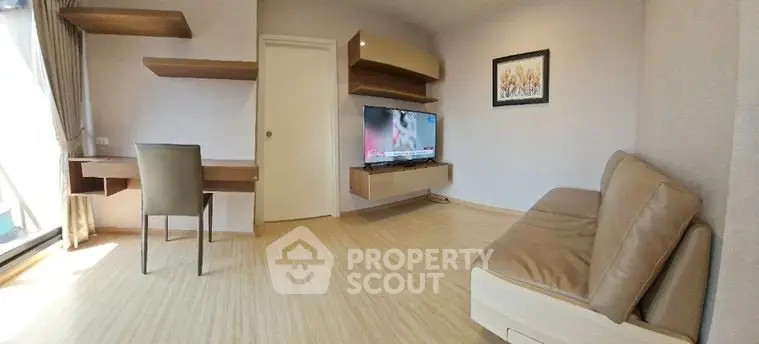 Modern living room with sleek furniture and wall-mounted TV, featuring a cozy workspace and natural light.