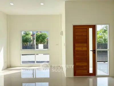 Bright and airy living room with large windows and wooden door, perfect for natural light lovers.