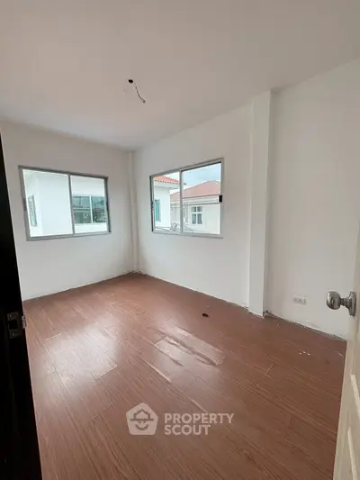 Spacious unfurnished room with wooden flooring and large windows for natural light.