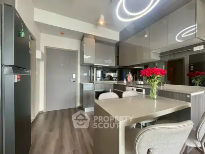 Modern kitchen with sleek cabinetry and dining area featuring elegant lighting and floral centerpiece.