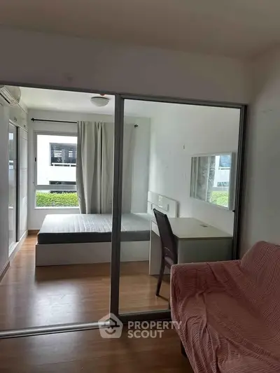Cozy bedroom with glass partition, modern furnishings, and natural light, perfect for urban living.