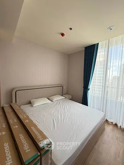 Modern bedroom with large window and natural light in high-rise apartment