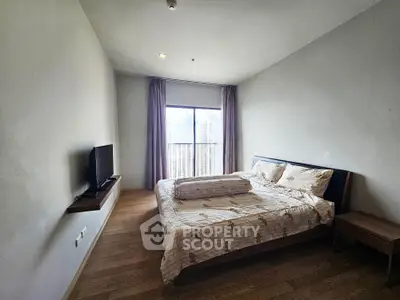 Spacious bedroom with city view, featuring a cozy bed and modern TV setup, perfect for urban living.