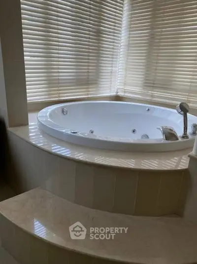 Luxurious bathroom with corner jacuzzi tub and elegant blinds, perfect for relaxation.