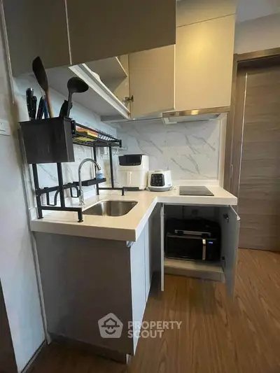 Compact modern kitchen with sleek appliances and marble backsplash, perfect for urban living.