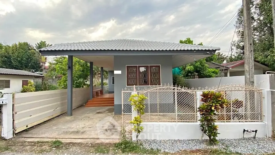 Charming single-story home with gated entrance and lush greenery.