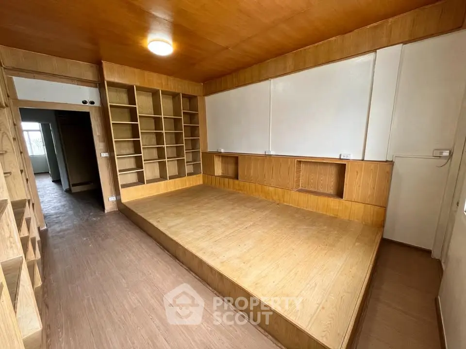 Spacious wooden interior with built-in shelving and platform bed, perfect for modern living.