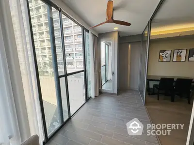 Spacious and well-lit corner unit with large windows, modern tile flooring, and a sleek ceiling fan, offering a panoramic city view.