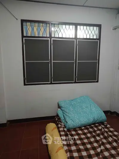 Cozy bedroom with simple bedding and large window, perfect for natural light lovers.