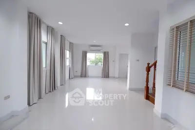 Spacious modern living room with large windows and elegant staircase