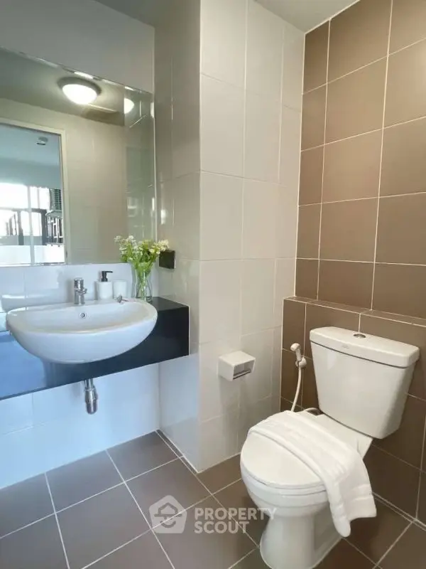 Modern bathroom with sleek fixtures and neutral tiles, featuring a stylish sink and toilet.