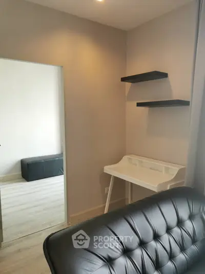 Modern study nook with sleek black shelves and leather chair in a stylish apartment.