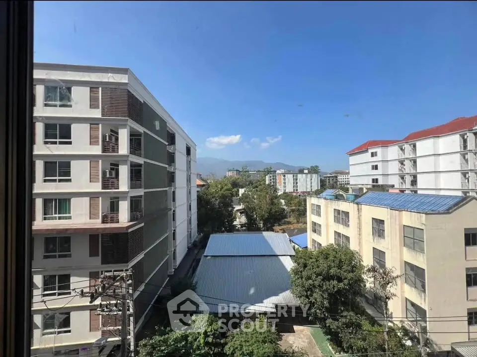 Stunning urban view from high-rise apartment window showcasing modern buildings and clear blue sky.