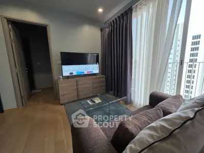 Modern living room with cozy sofa, flat-screen TV, and floor-to-ceiling windows offering city views.