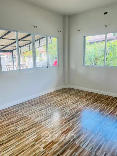 Spacious room with large windows and stylish wooden flooring