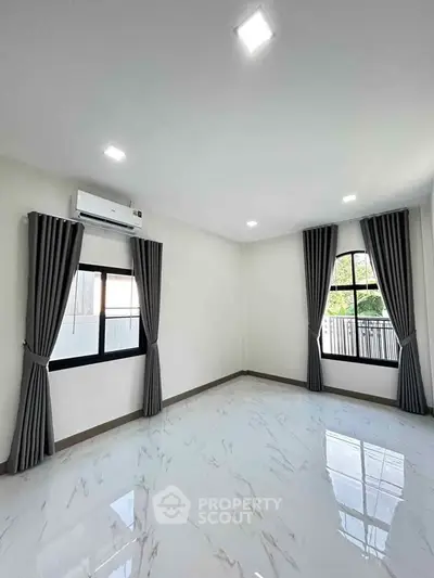 Spacious modern living room with large windows and elegant curtains, featuring sleek tile flooring and ample natural light.