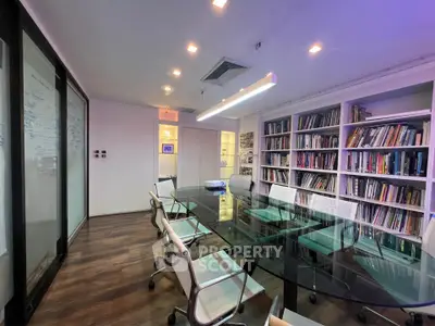Modern study room with glass table and bookshelves in a sleek office setting.