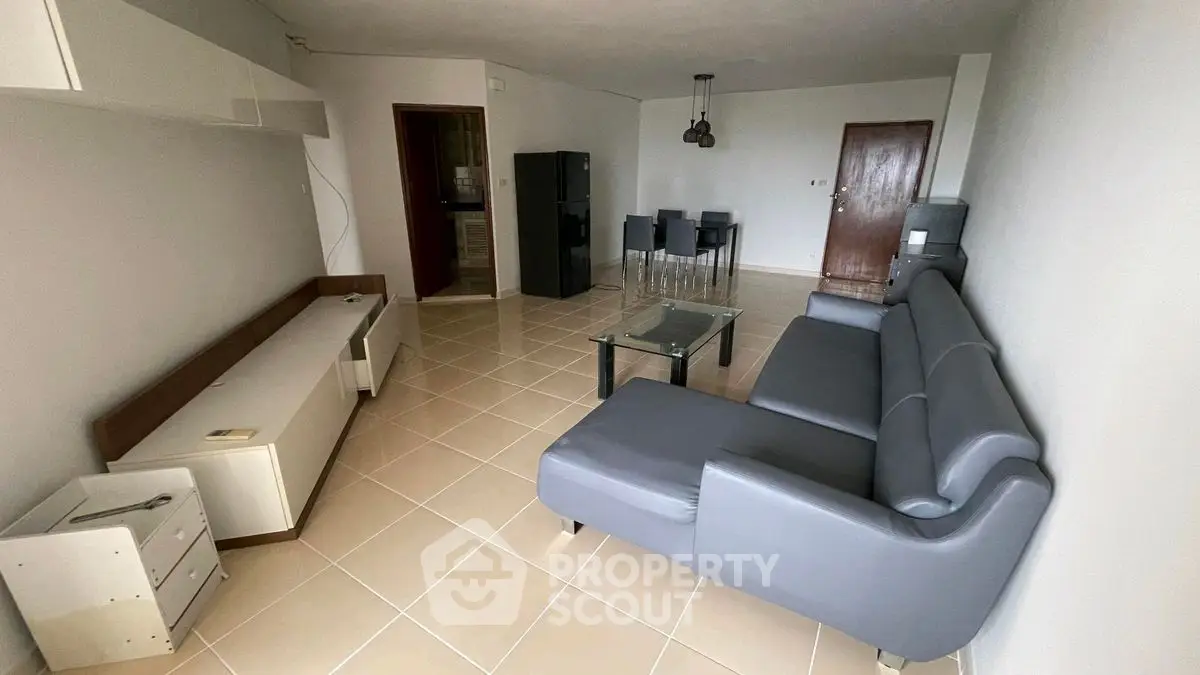Spacious living room with modern gray sofa and dining area, ideal for comfortable living.