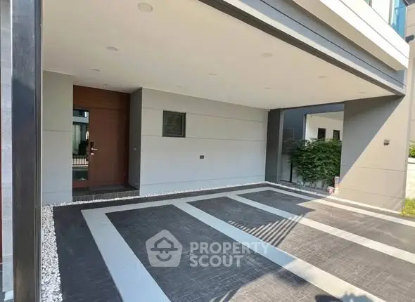 Modern house entrance with spacious covered parking area and sleek architectural design.