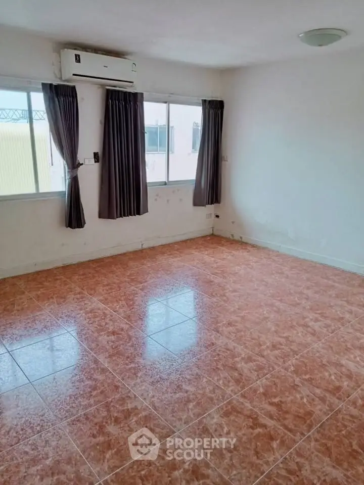 Spacious empty room with tiled floor and large windows, perfect for customization.