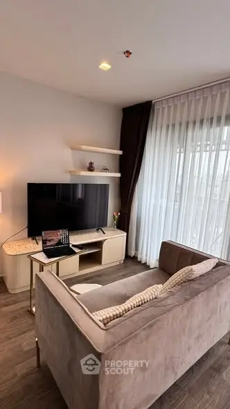 Modern living room with cozy sofa and large TV, featuring elegant curtains and stylish decor.