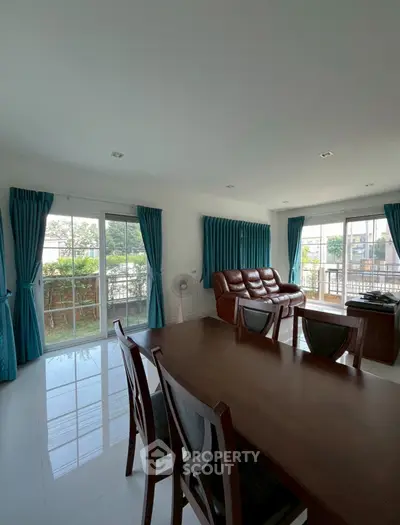 Spacious living room with elegant furniture and large windows offering garden views.