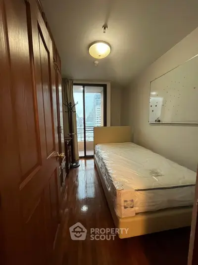 Cozy bedroom with city view, featuring a single bed and wooden flooring, perfect for urban living.