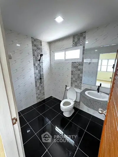 Modern bathroom with sleek black and white tiles, featuring a shower and stylish sink.