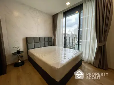 Modern bedroom with large window and city view, featuring elegant decor and natural light.