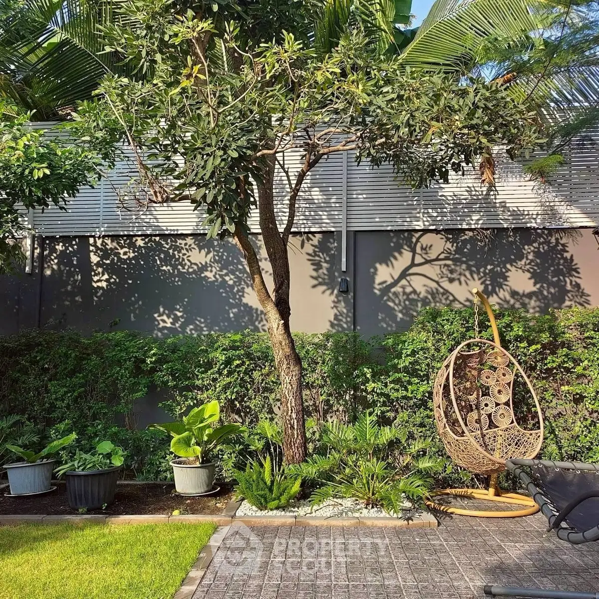 Lush garden with modern outdoor seating and tropical plants, perfect for relaxation and leisure.