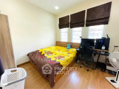 Cozy bedroom with wooden flooring, study desk, and natural light from windows.