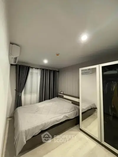 Modern bedroom with sleek design, featuring a comfortable bed and mirrored wardrobe.