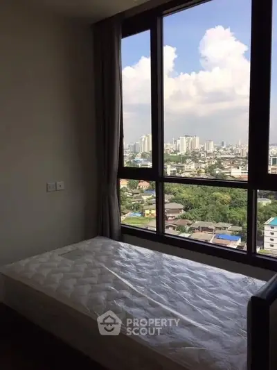 Spacious bedroom with large window offering stunning city view