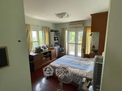 Cozy bedroom with natural light and wooden flooring, featuring a comfortable bed and ample storage space.