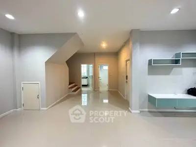 Spacious modern living area with sleek design and staircase leading to upper level.