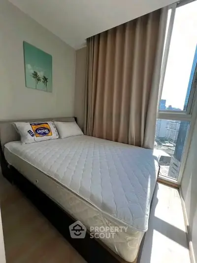Bright and cozy bedroom with large window offering city views, perfect for urban living.