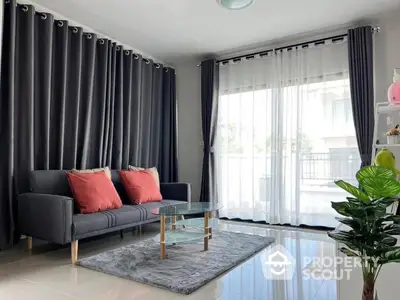 Modern living room with stylish sofa and glass coffee table, featuring floor-to-ceiling windows and elegant curtains.