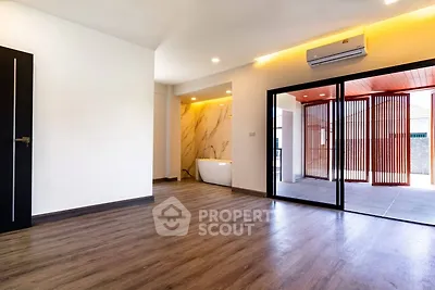 Spacious modern living area with wooden flooring and large windows.