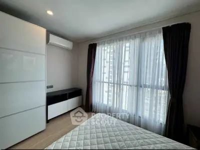 Modern bedroom with large window and sleek furniture in a high-rise apartment.