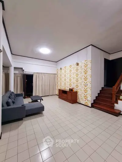Spacious living room with modern decor and staircase, perfect for family gatherings.