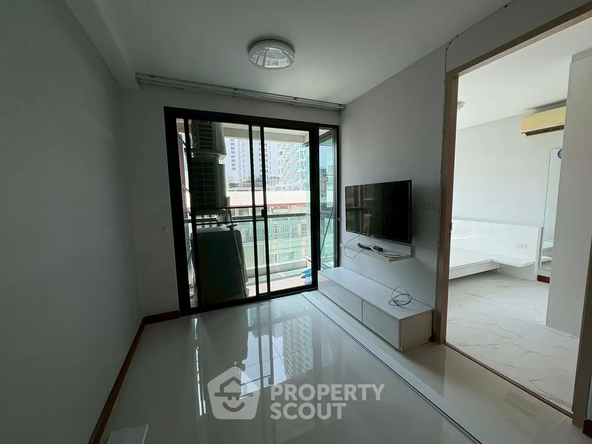 Modern living room with balcony and sleek TV setup in urban apartment