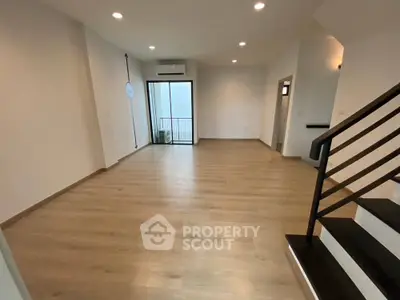 Spacious modern living room with wooden flooring and balcony access