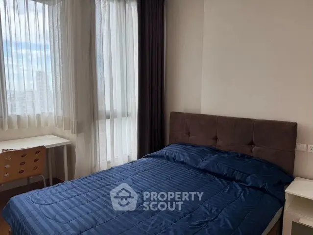 Modern bedroom with large window and stylish furnishings in a high-rise apartment.