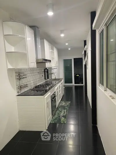 Modern kitchen with sleek black tiles and white cabinetry featuring a gas stove and oven.