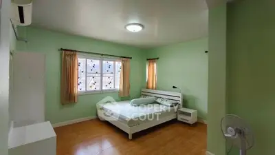 Spacious bedroom with green walls, natural light, and minimalist decor.