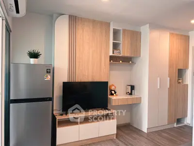 Modern living room with sleek wooden cabinetry and flat-screen TV, featuring a compact fridge and stylish decor.