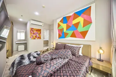 Modern bedroom with colorful geometric art and cozy bedding in a stylish apartment.